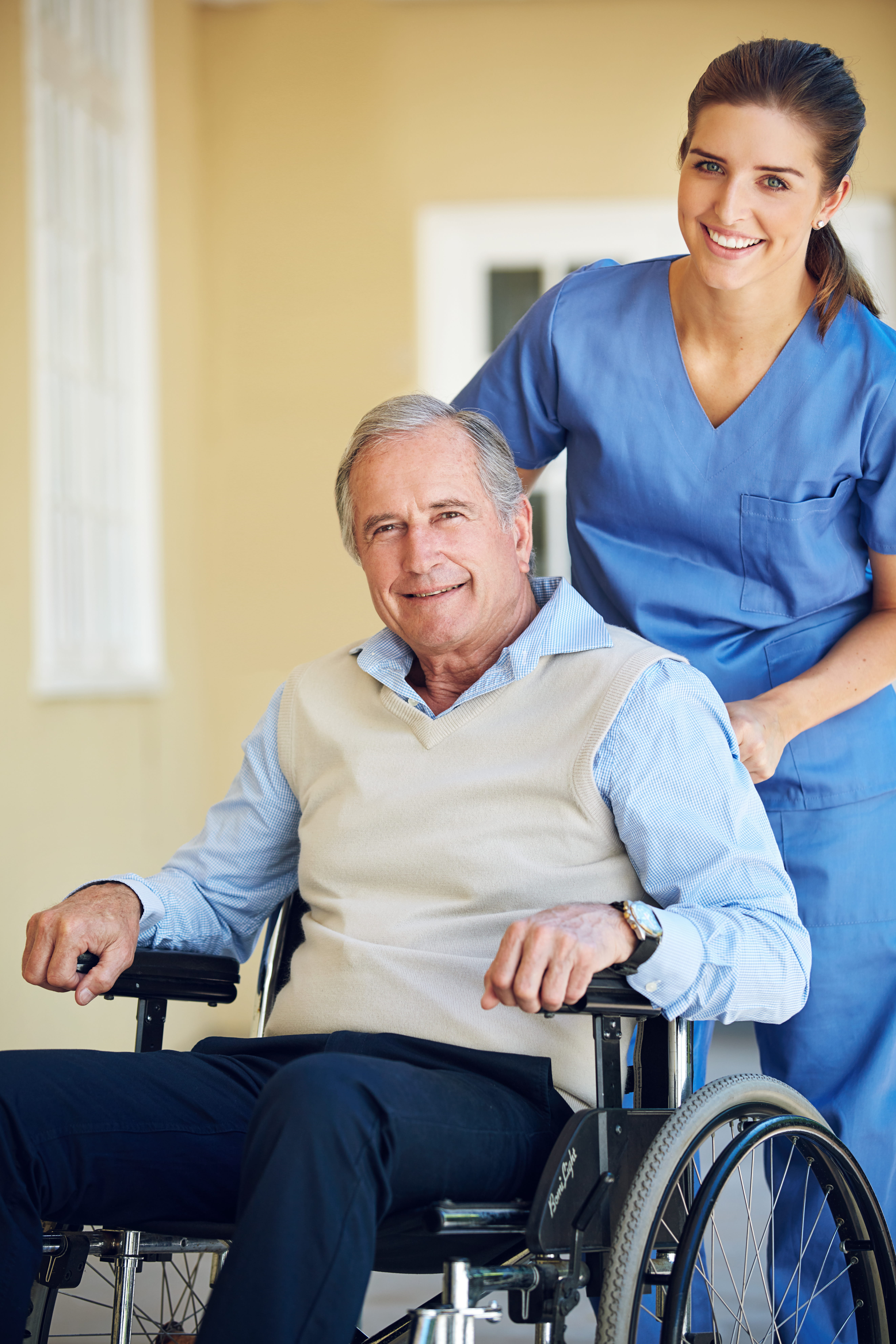 Female caregiver pushing a senior male resident in his wheelchair.