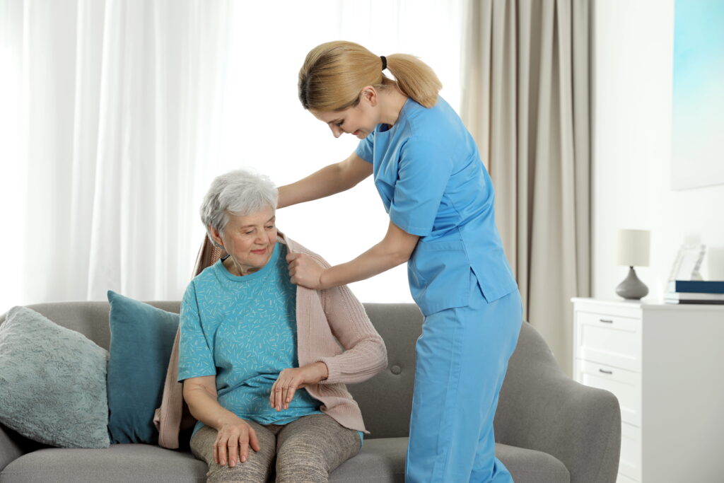 Caregiver helping put on coat for senior female resident.