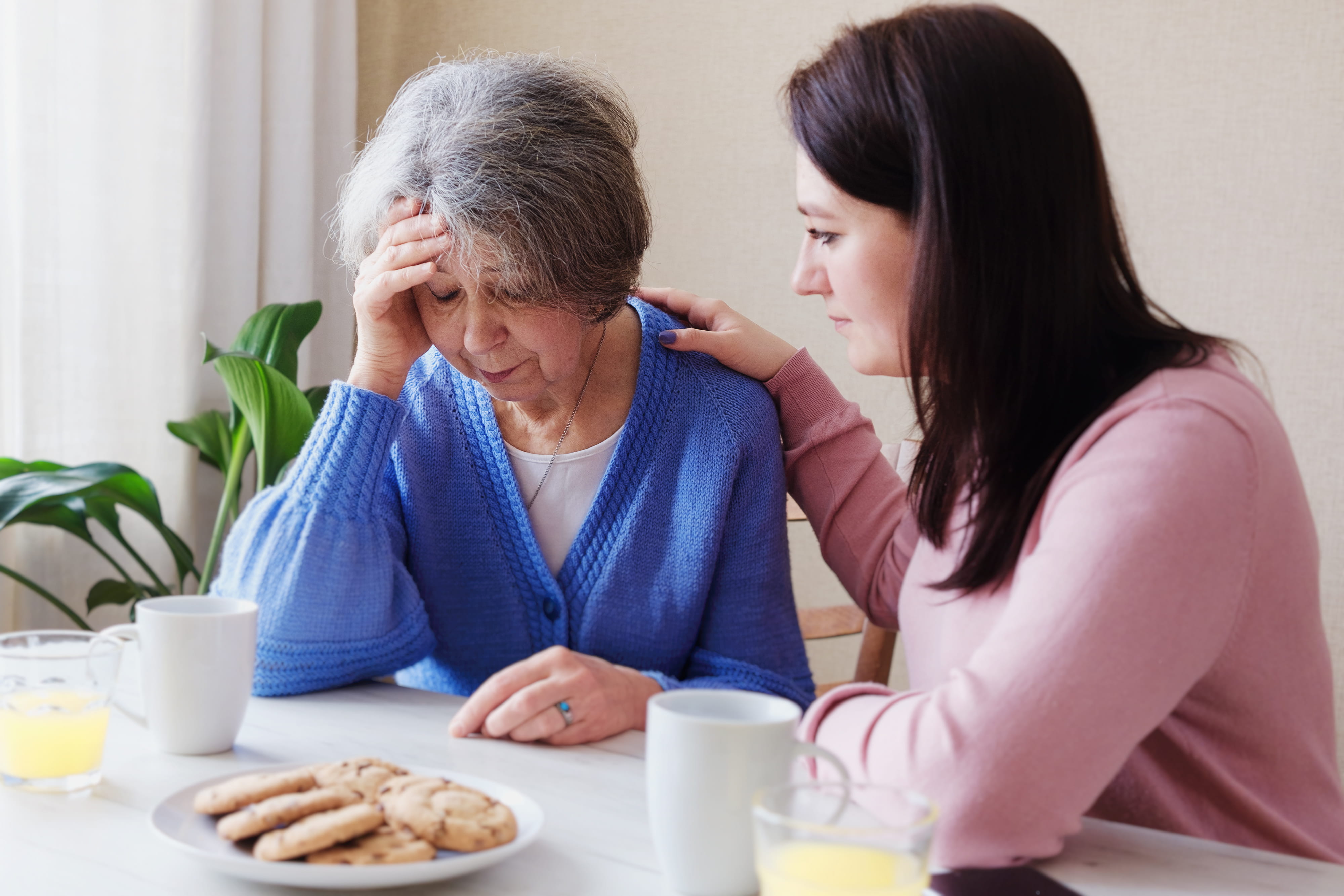 Adult daughter consoling her senior mom.