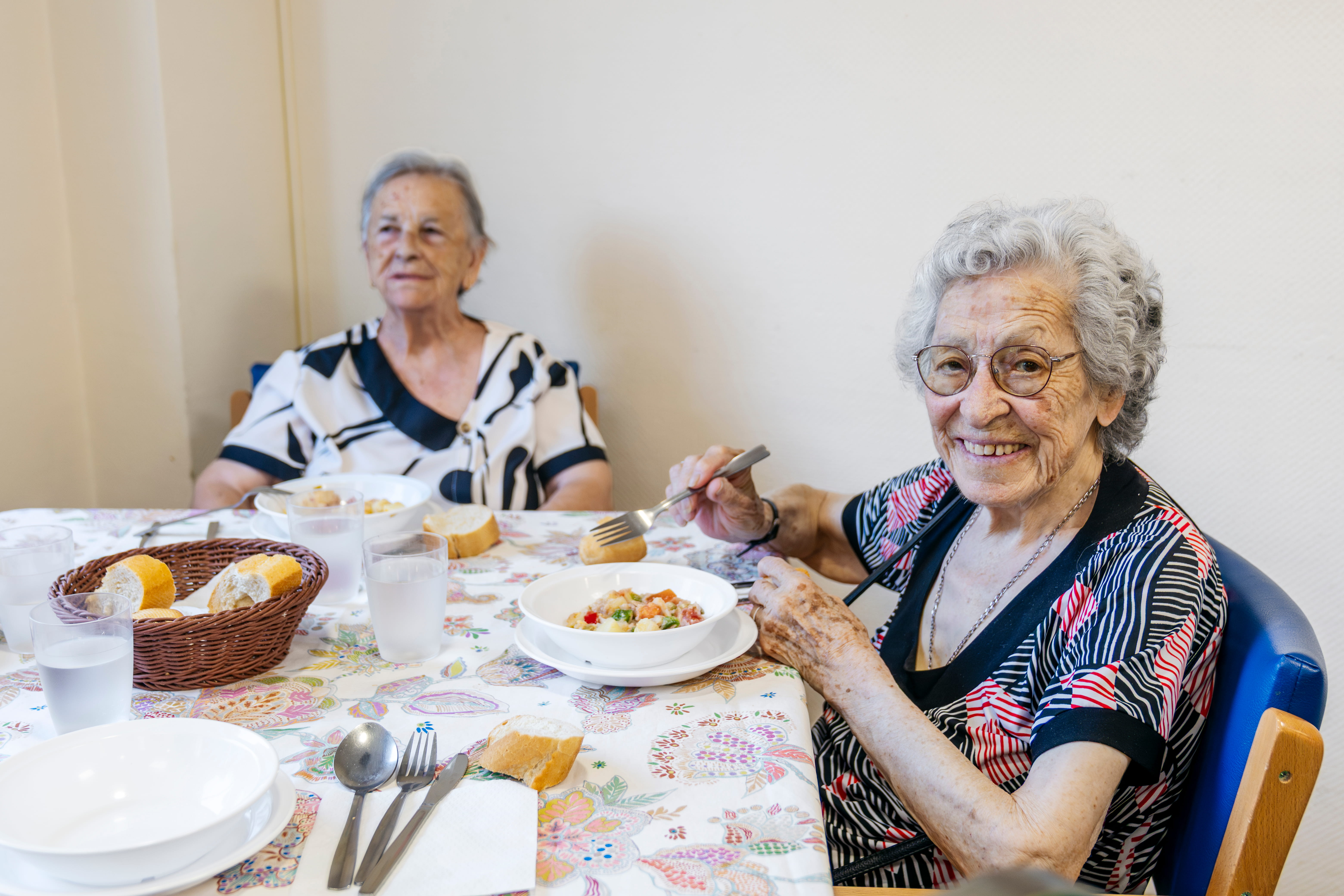 Two senior women eating at a table together.