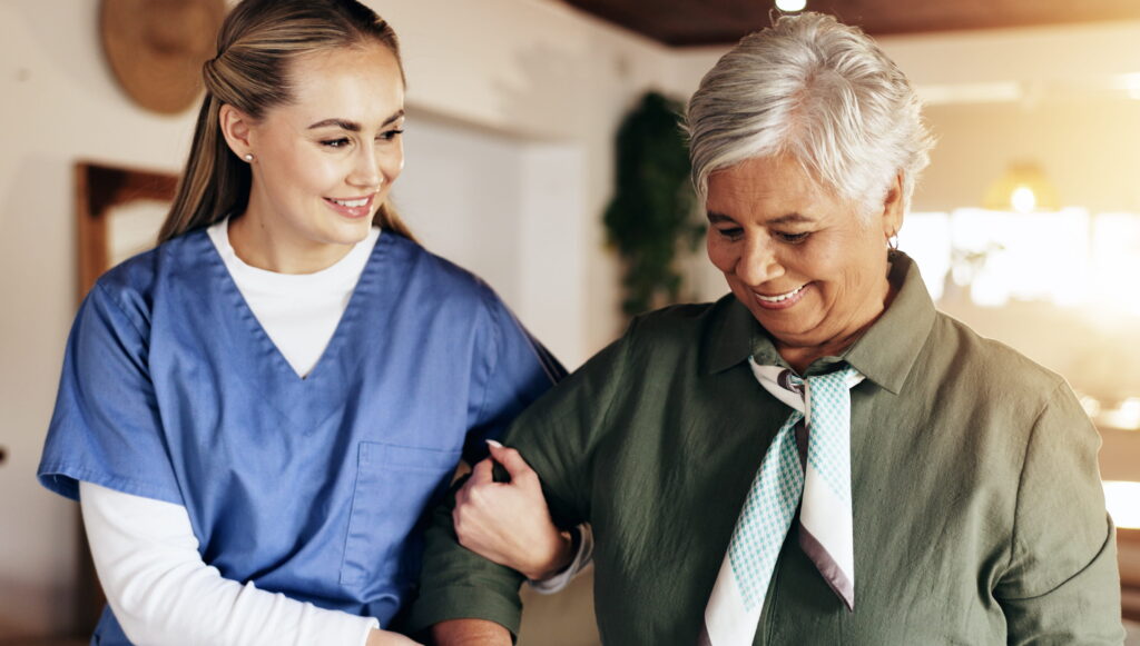 Caregiver helping female resident walk.
